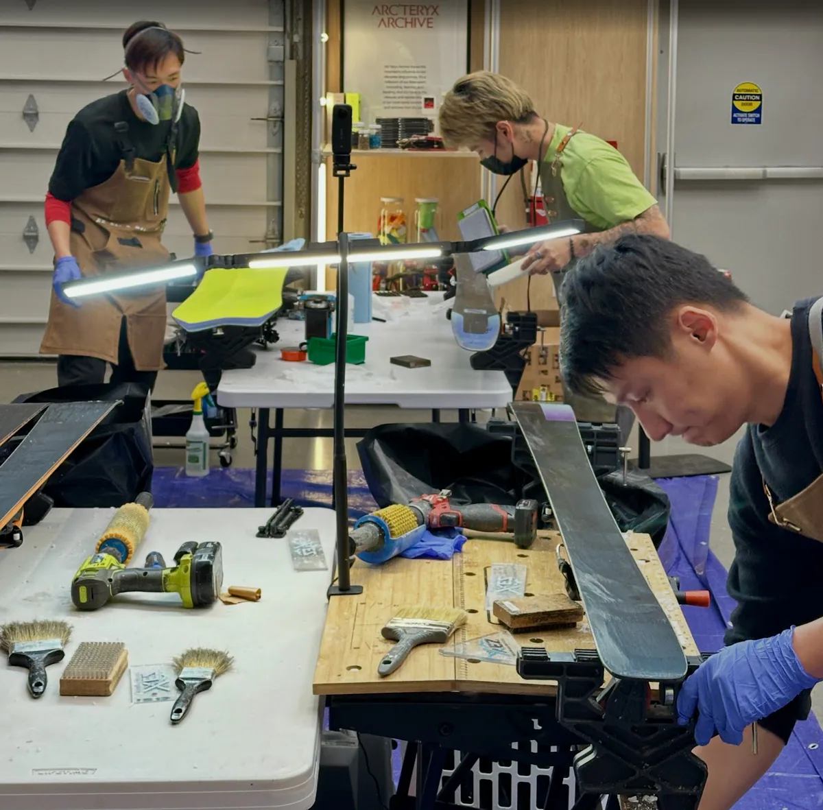Technicians servicing skis and snowboards at an event workbench